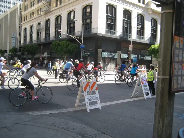 The picture is clicked on a road where there are several people riding bicycles and in the...